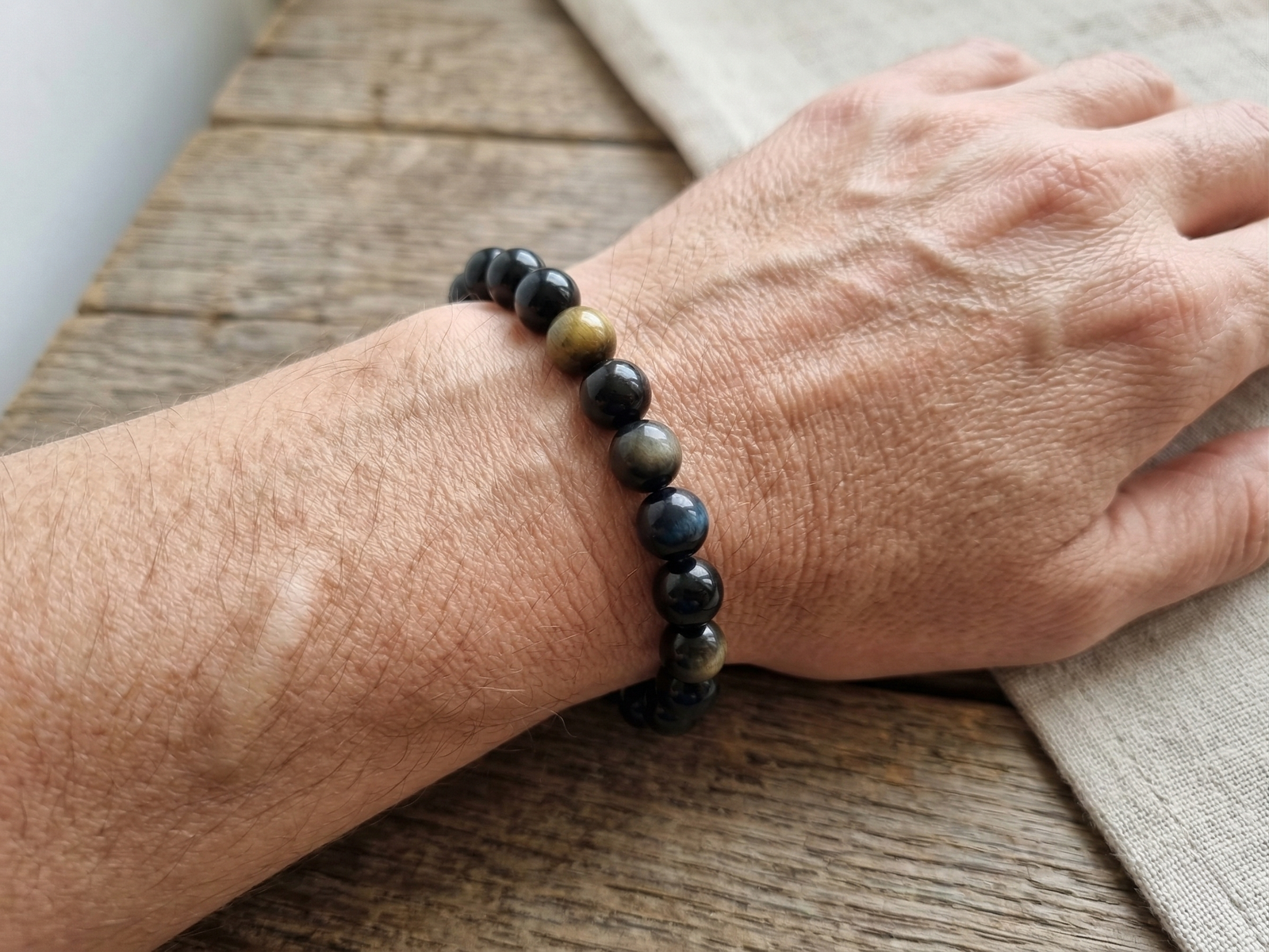 Bracelet lithotherapie Obsidienne oeil celeste sur poignet par Romain Creation